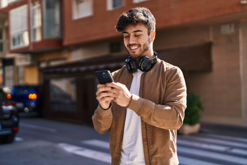 young hispanic man smiling confident using smartphone street scaled e1761751861564